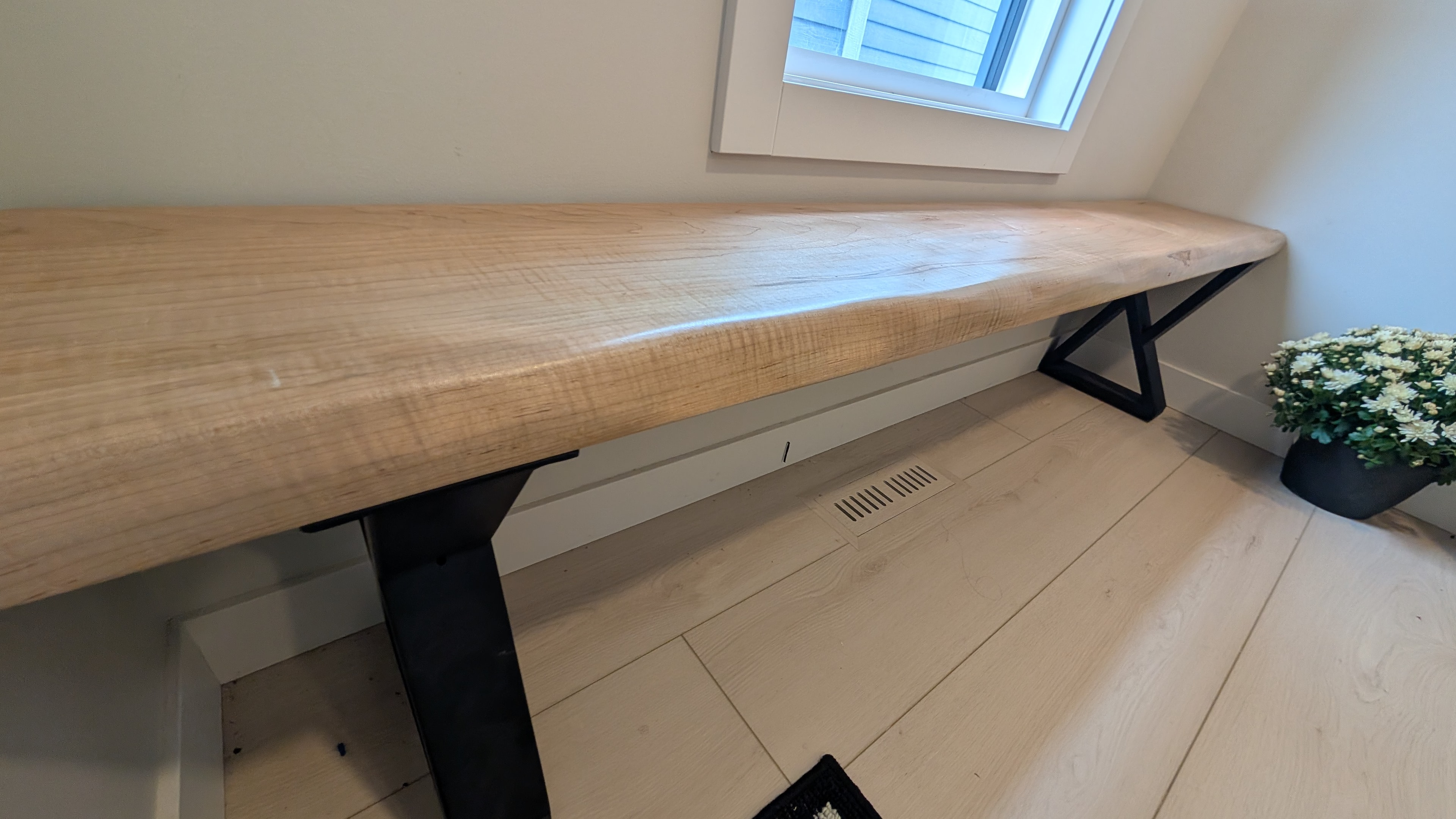 Close-up of solid maple bench top with live edge detail and black X-base — Calgary