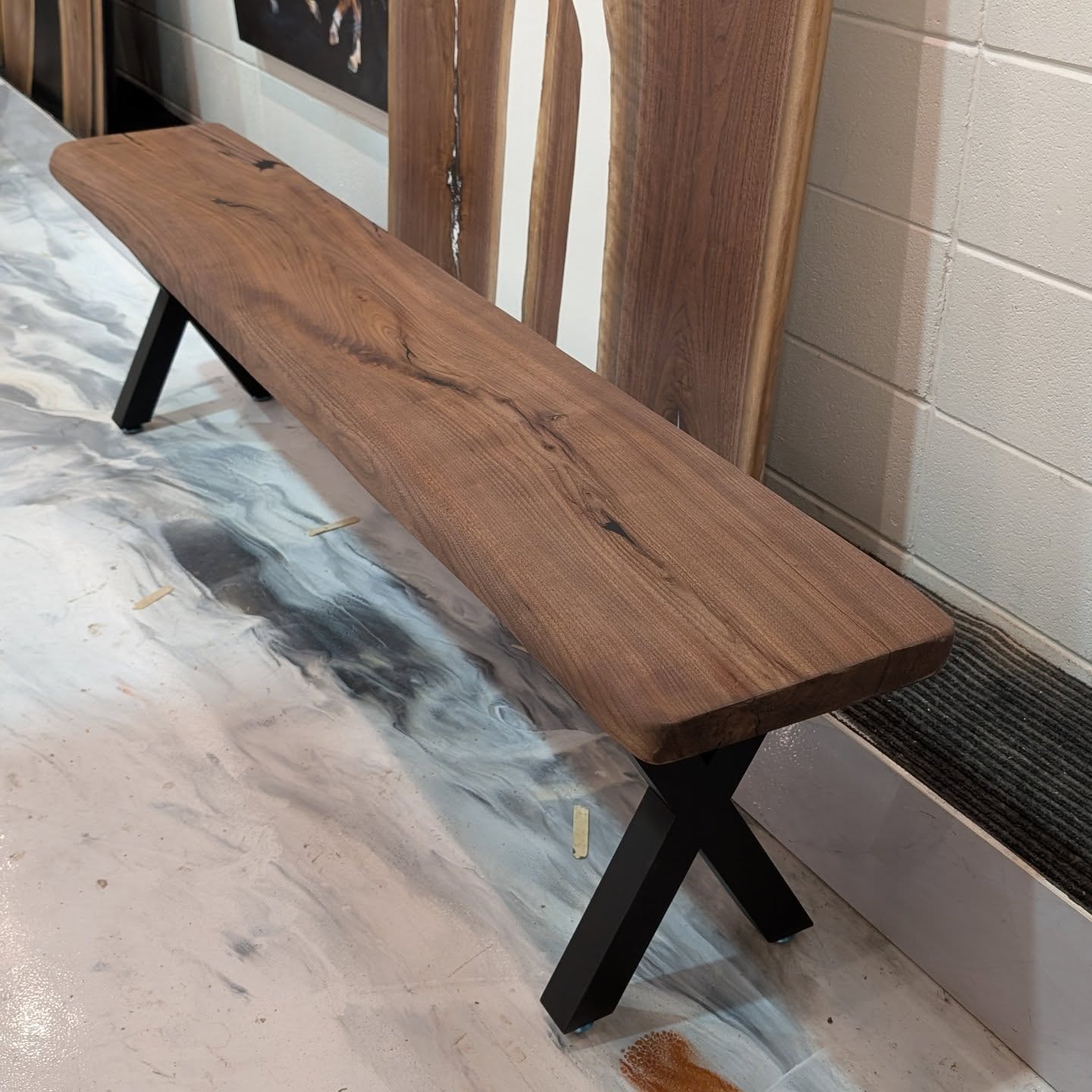 Matching pair of live edge walnut benches with black X-base legs on epoxy shop floor — Calgary Wood Works