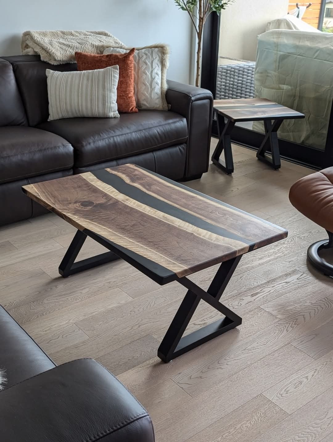 Live edge walnut black epoxy end table beside dark leather sofa