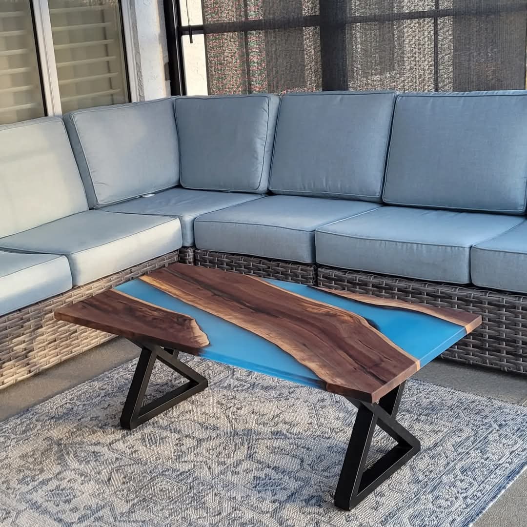 Live edge walnut blue epoxy river coffee table with Z-base on outdoor covered patio with blue sectional