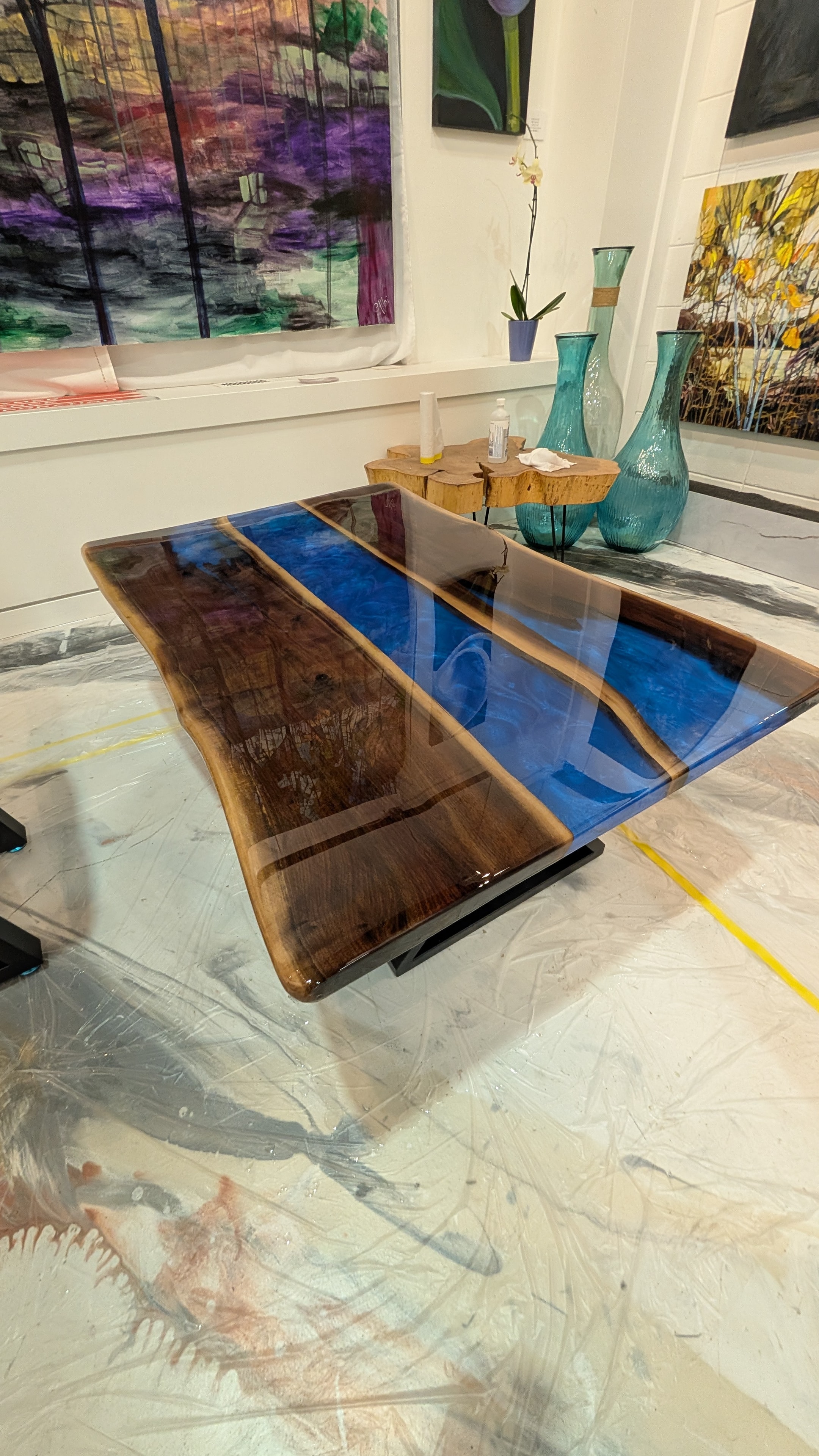Live edge walnut triple blue epoxy river coffee table — dramatic overhead shop view with vivid blue channels