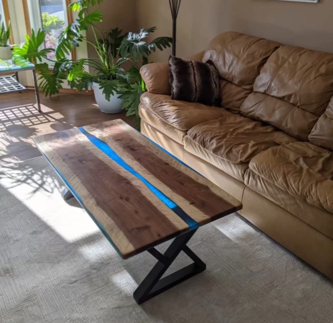 Live edge walnut blue epoxy river coffee table with Z-base in plant-filled sunny living room