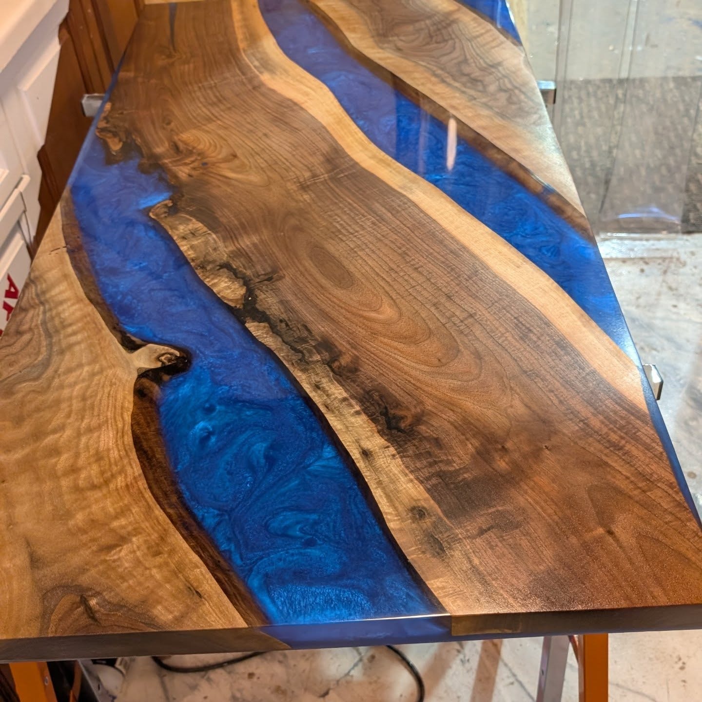 Bookmatched live edge walnut coffee table with deep blue metallic epoxy river — stunning grain closeup at Calgary Wood Works