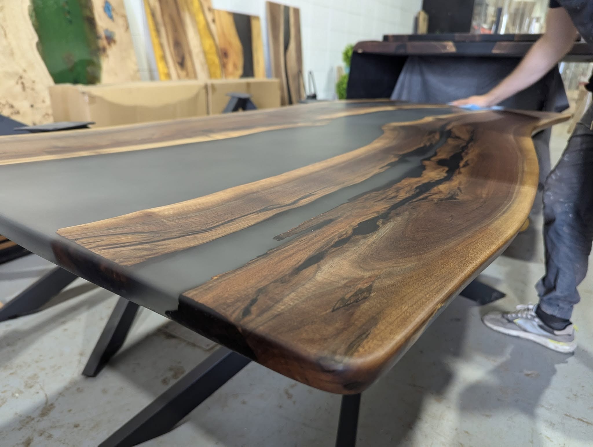 Live edge walnut coffee table with grey epoxy river inlay being finished — Calgary Wood Works shop closeup