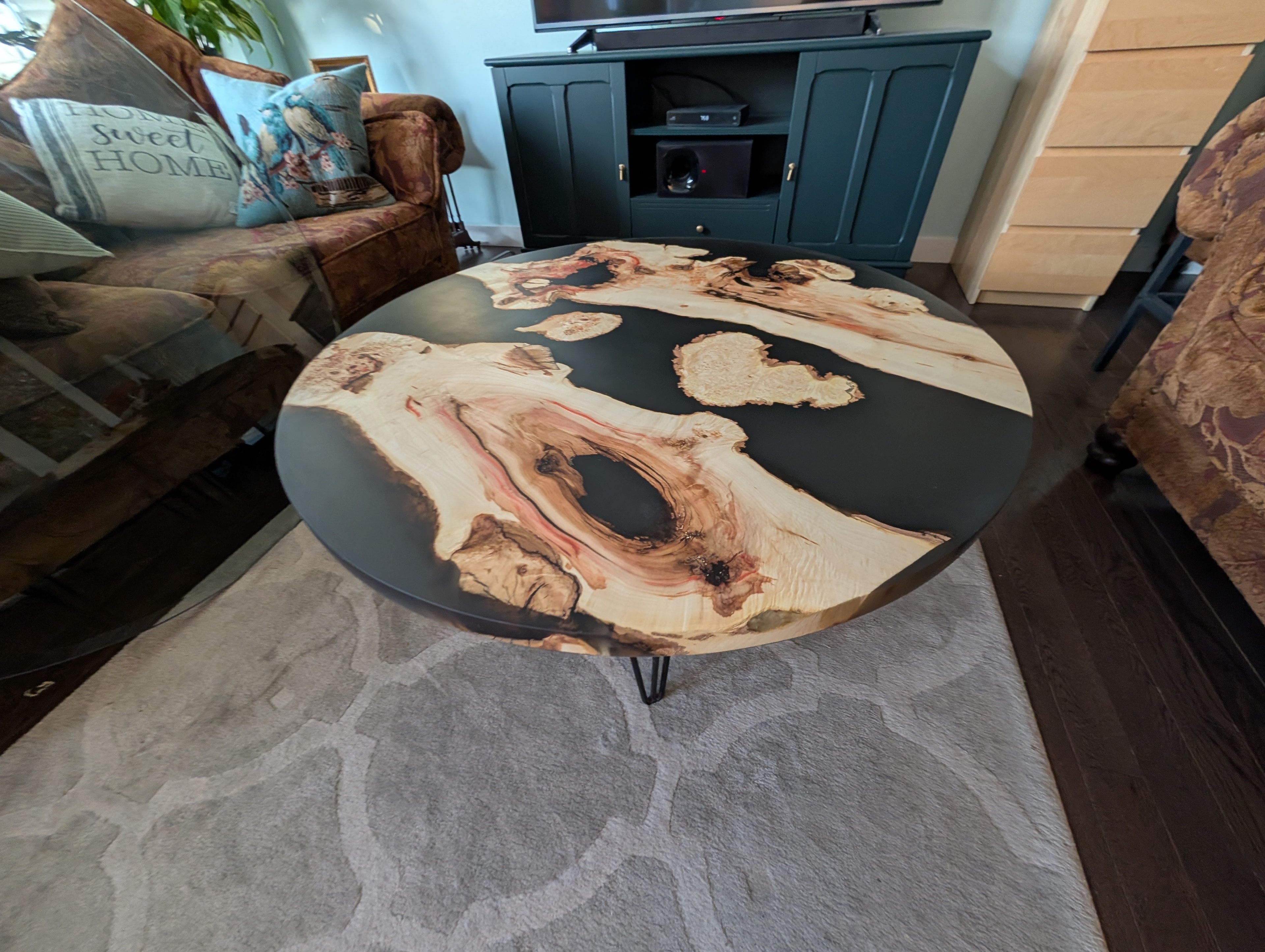 Round maple burl black epoxy coffee table with hairpin legs in cozy living room