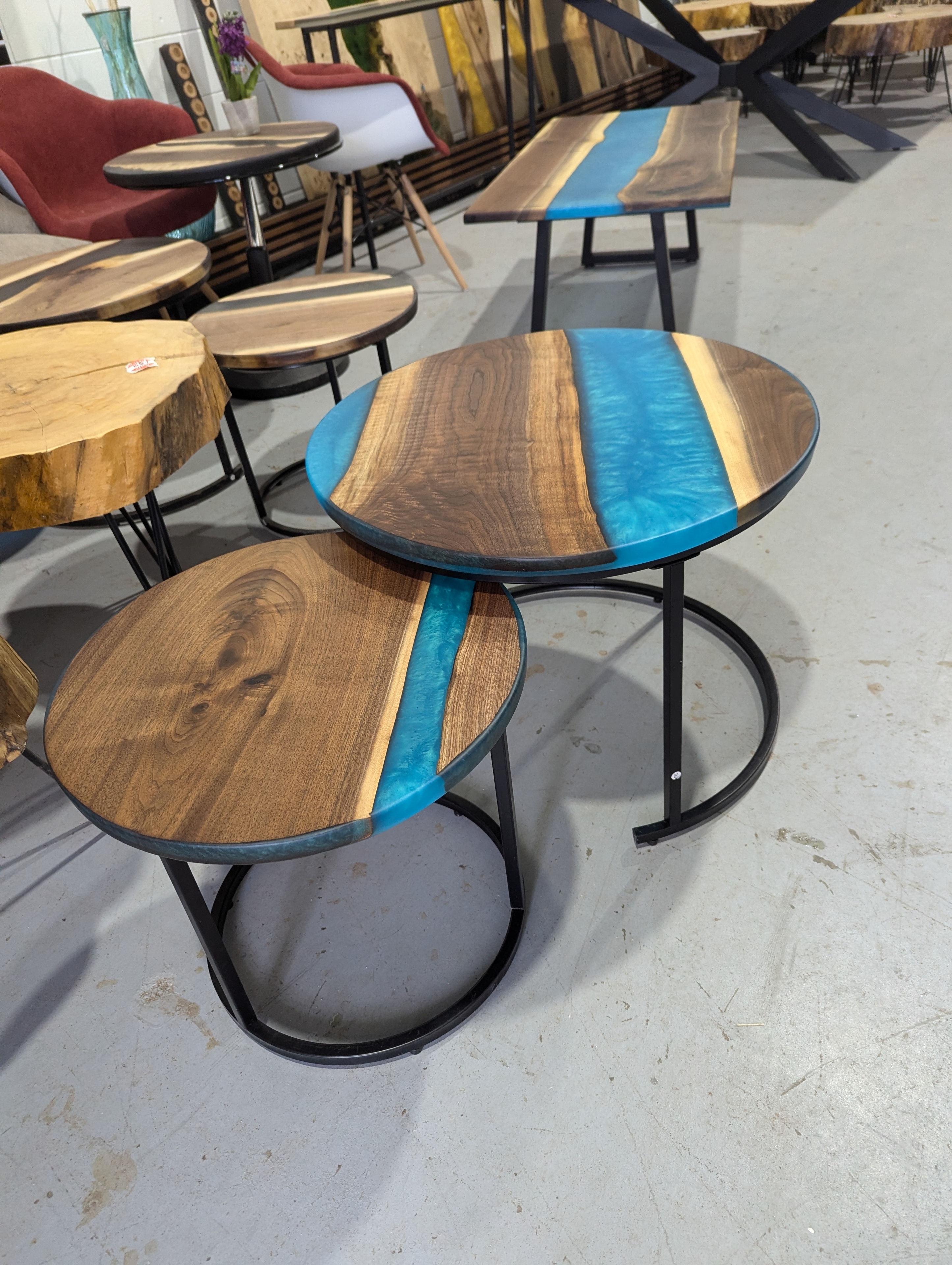Three-piece round walnut blue epoxy nesting coffee table set in Calgary Wood Works showroom