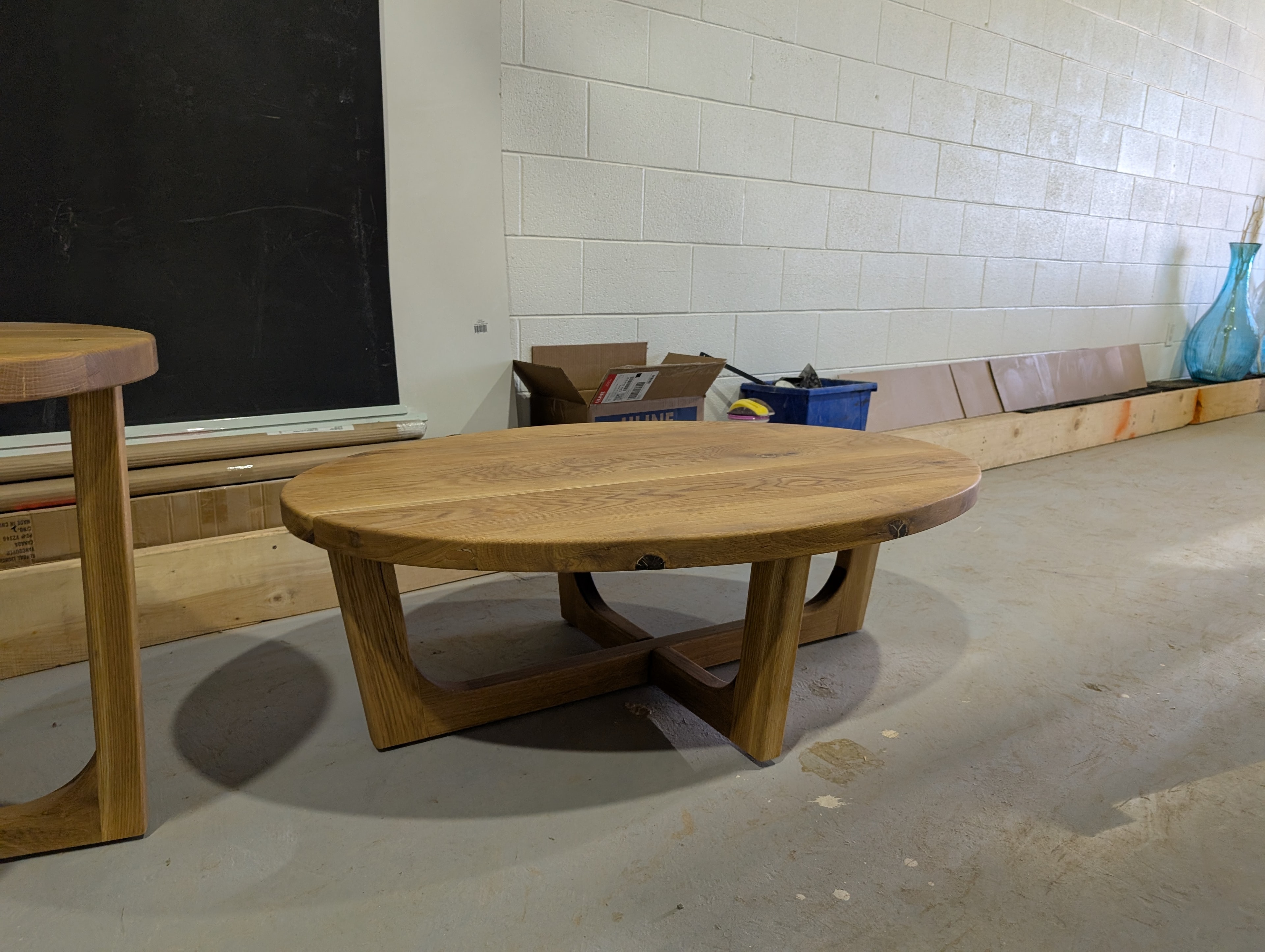 Round solid elm coffee table with sculpted X-base in Calgary Wood Works shop