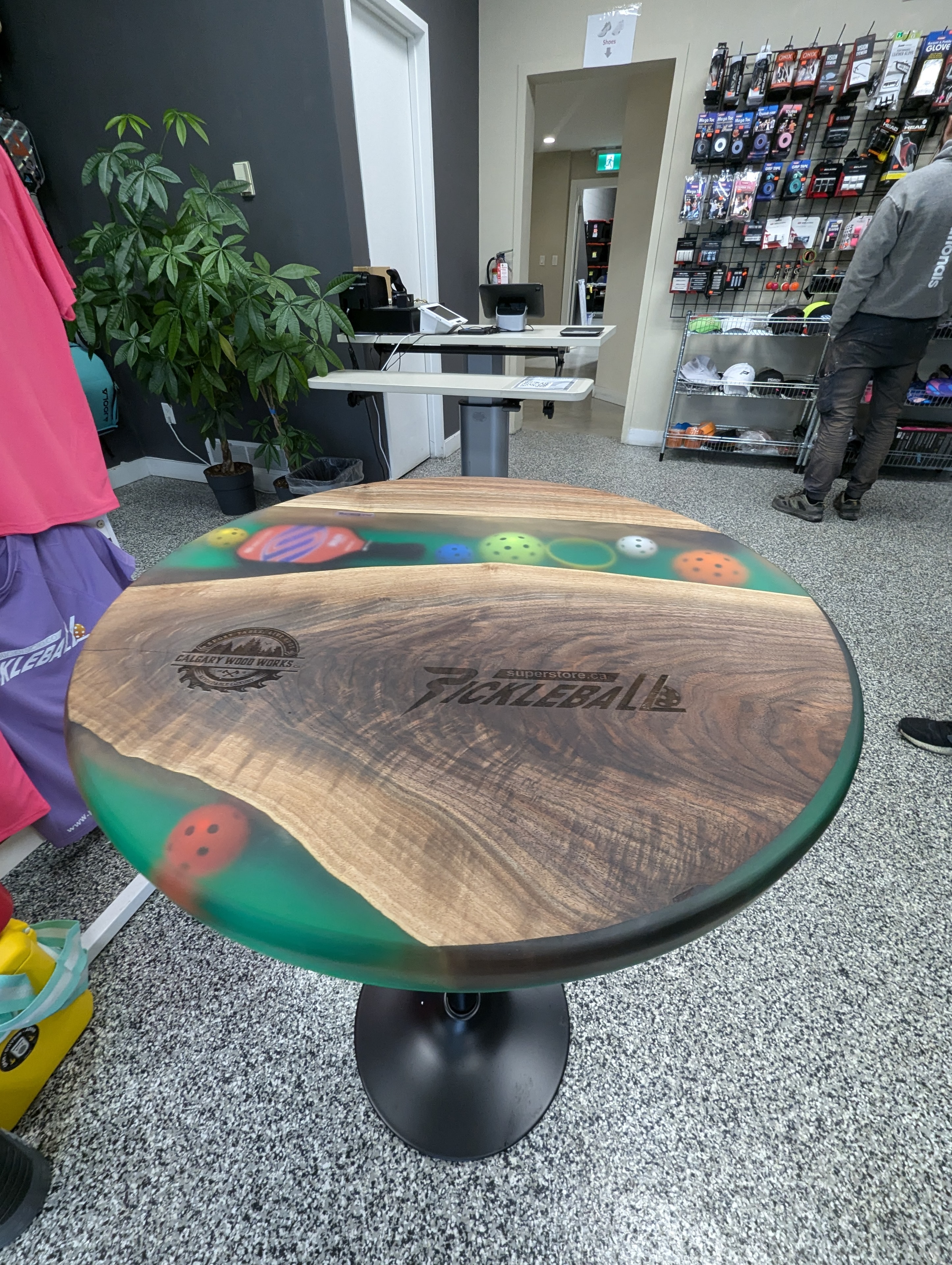 Custom round walnut green epoxy coffee table with engraved Calgary Wood Works and Pickleball Superstore logos