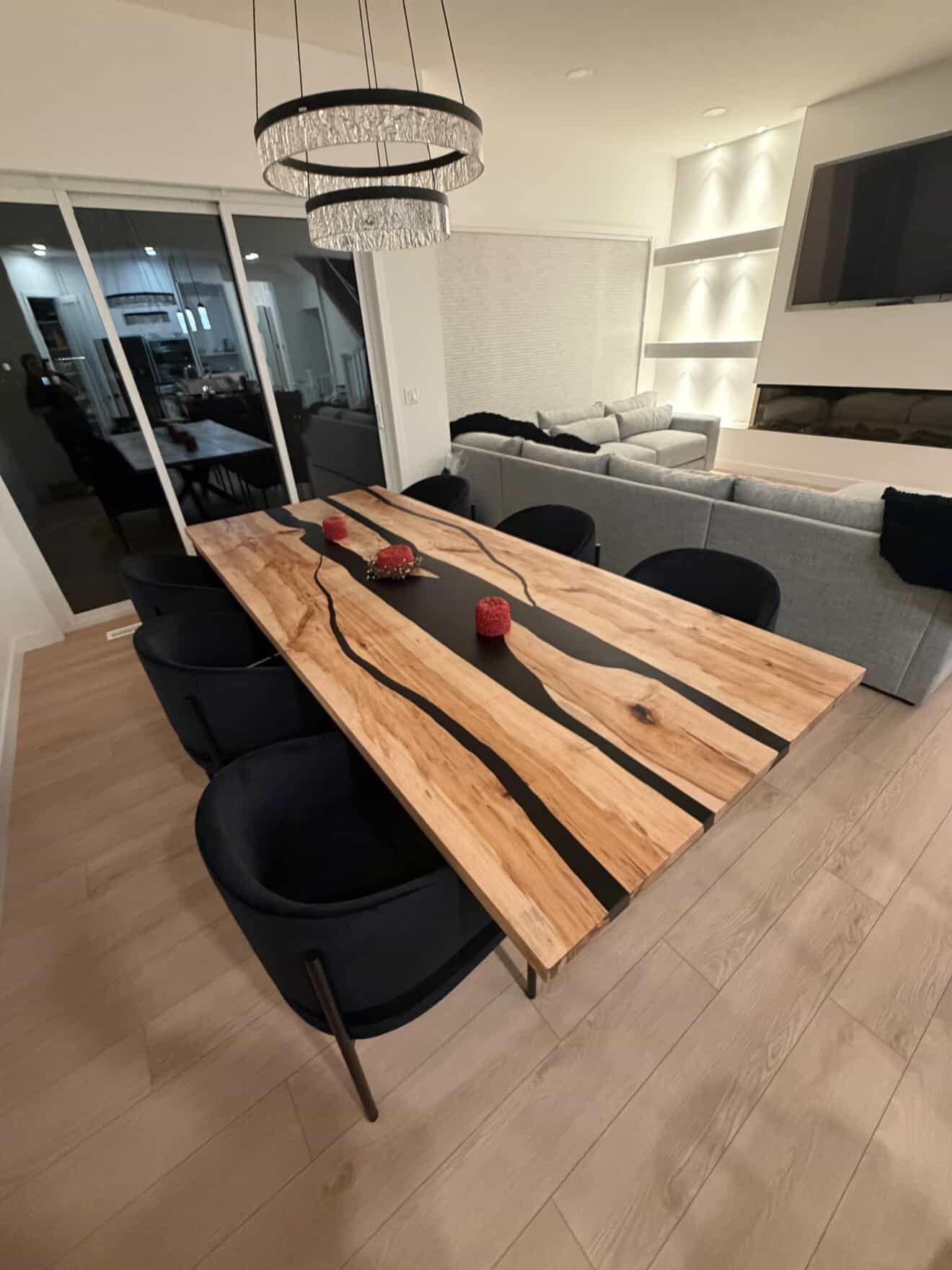Live edge elm triple-channel black epoxy river dining table under crystal chandelier