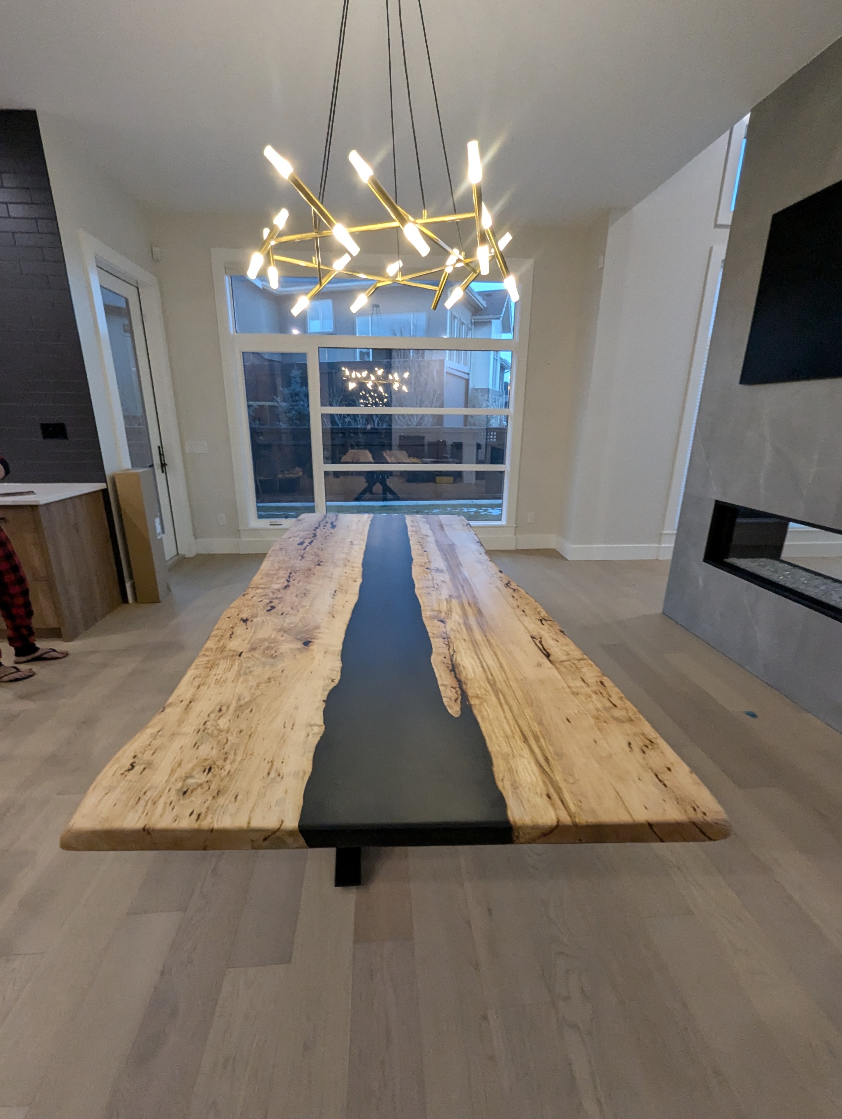 Massive maple burl black epoxy river dining table under gold chandelier