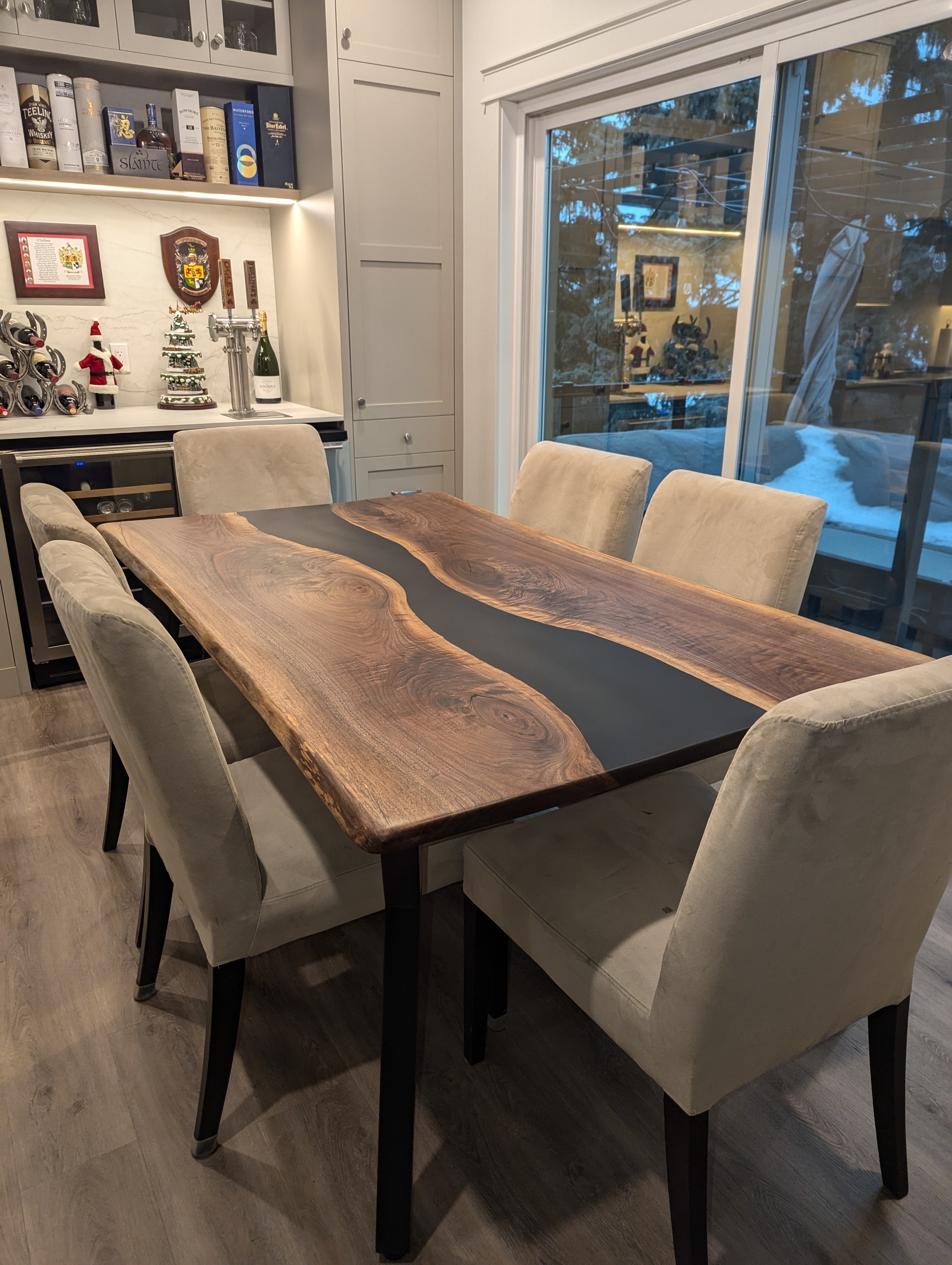 Black epoxy walnut river dining table with cream chairs and built-in bar cabinet
