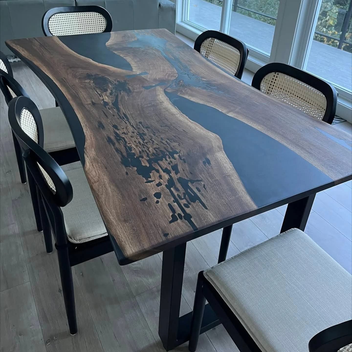 Live edge walnut black epoxy river dining table with black cane-back chairs