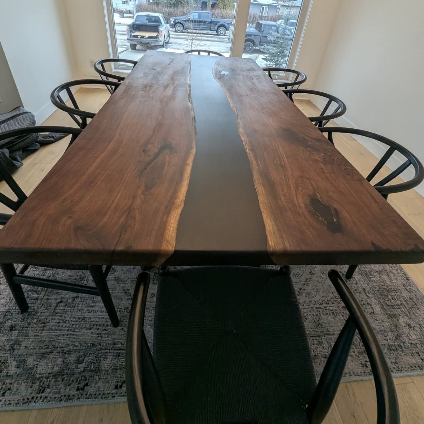 Live edge walnut black epoxy river dining table with black circle-back chairs