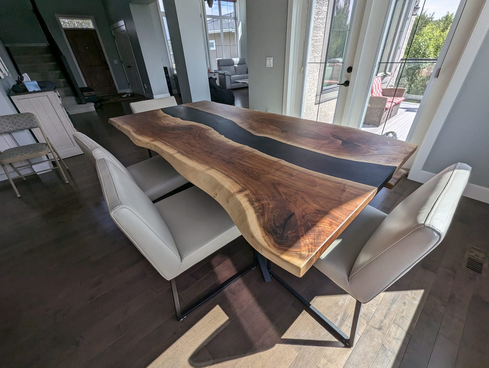 Live edge walnut black epoxy river dining table with cream leather chairs
