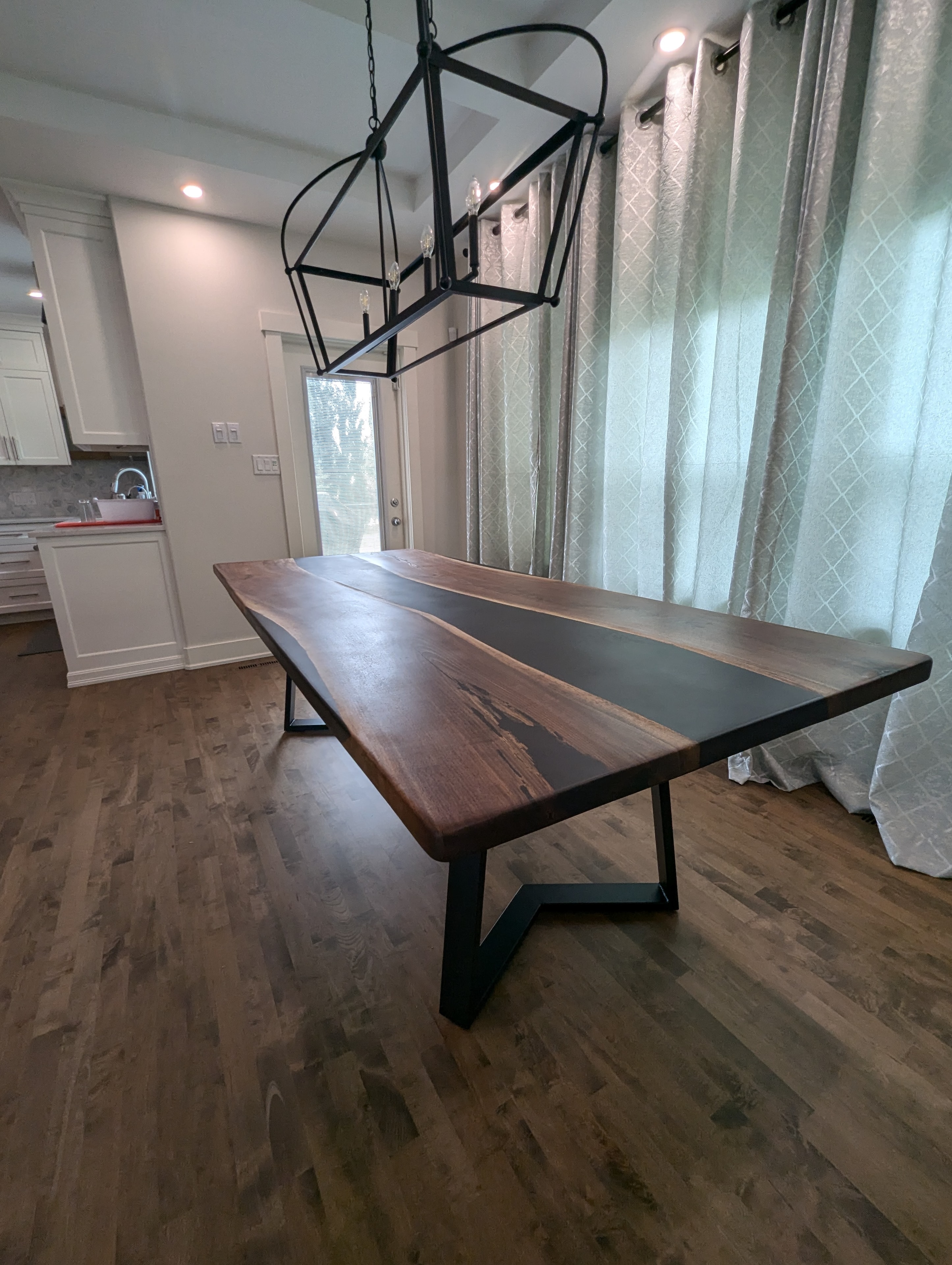 Black epoxy river walnut dining table with geometric lantern pendant and A-frame base