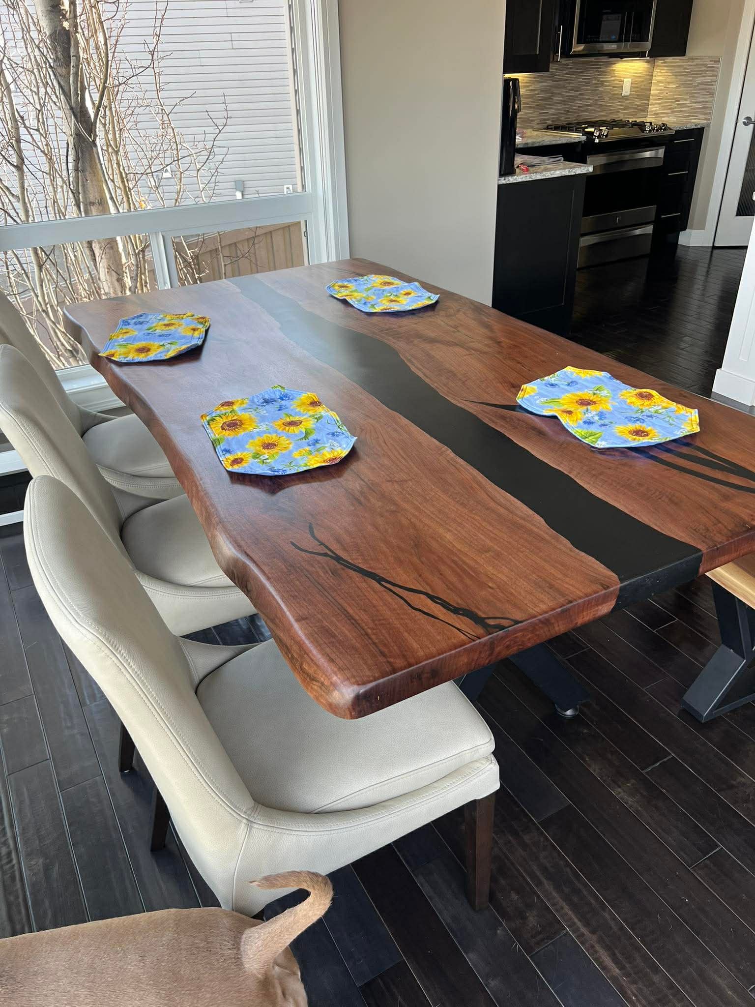 Live edge walnut black epoxy river dining table with white leather chairs and sunflower placemats