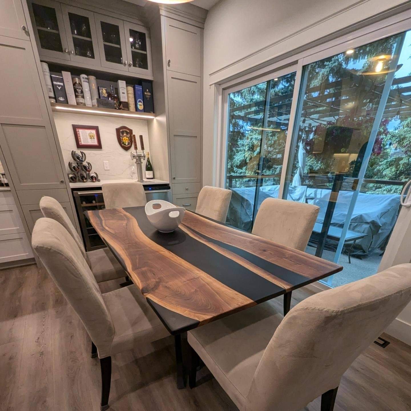 Live edge walnut black epoxy river dining table beside built-in wine bar and patio doors
