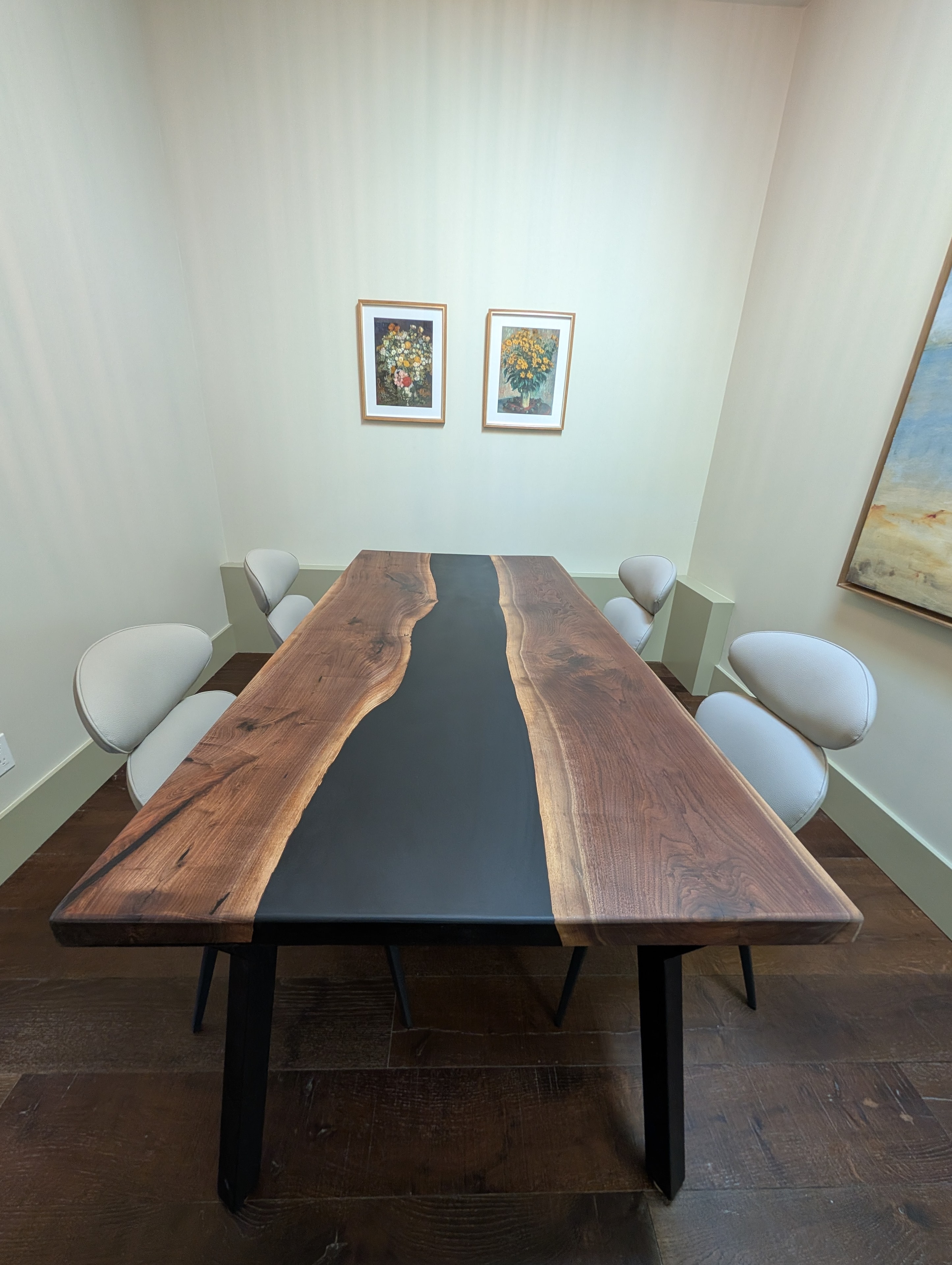 Black epoxy river walnut dining table with white upholstered chairs