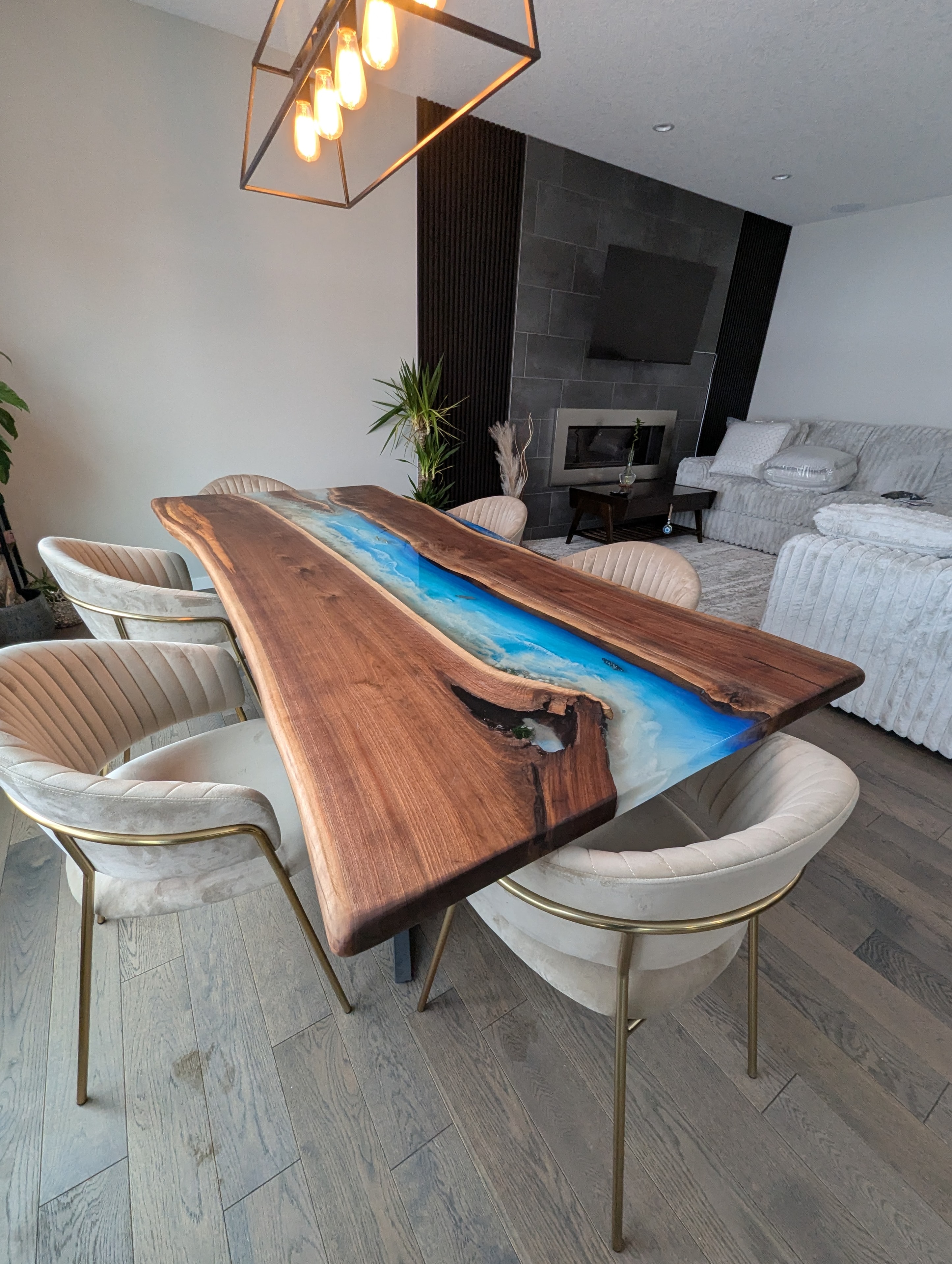 Live edge walnut blue epoxy river dining table with cream velvet and gold chairs