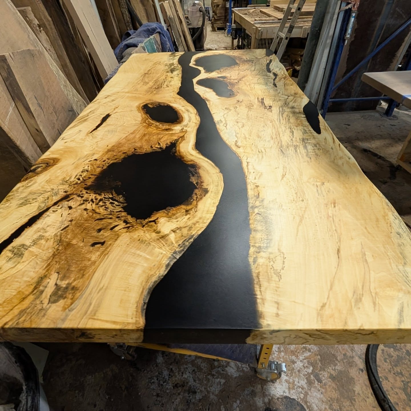 Spalted maple black epoxy river table with dramatic burl and knot inclusions — shop view at Calgary Wood Works