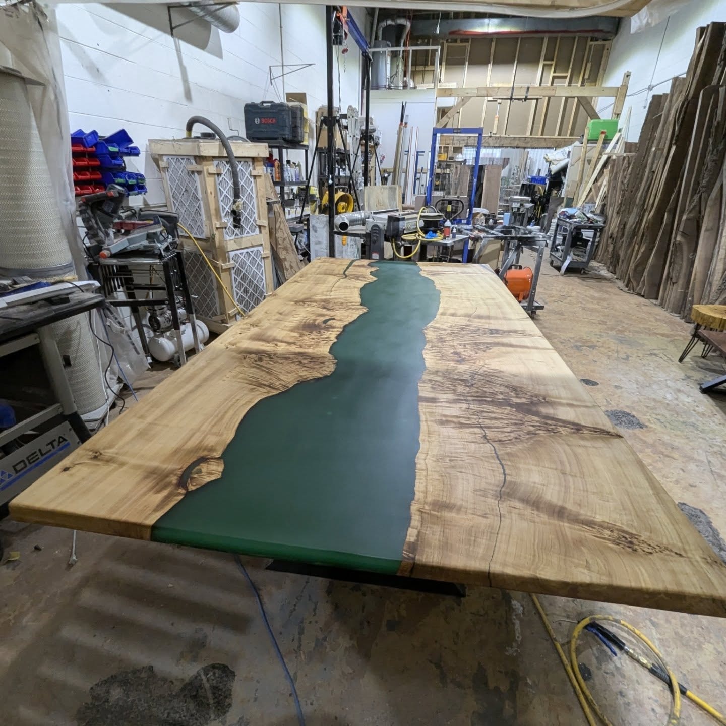 Live edge walnut black epoxy river dining table with spinback chairs — sunlit autumn view through windows