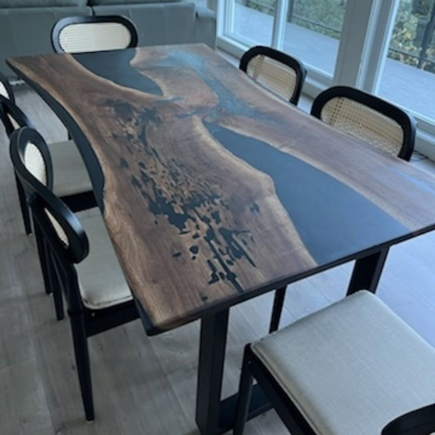 Live edge walnut black epoxy river dining table with white upholstered chairs — bright Calgary dining room