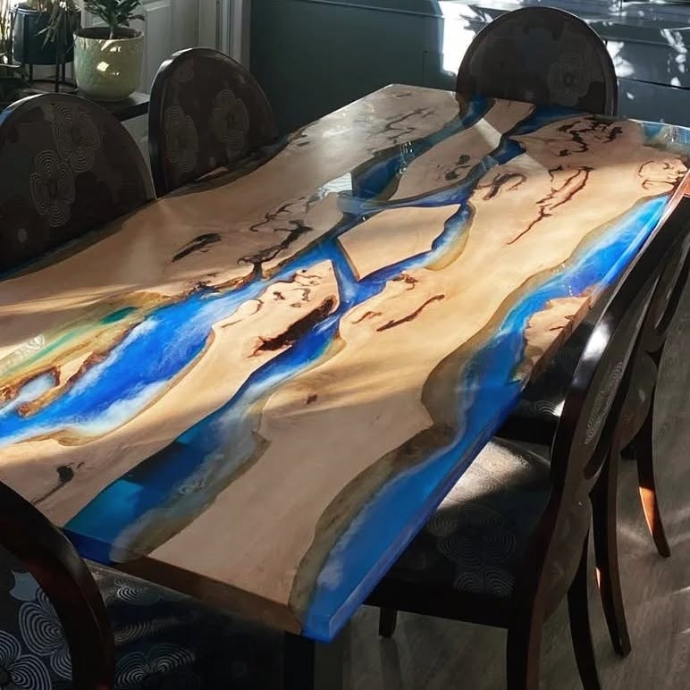 Spectacular maple burl blue and teal epoxy river dining table with dark carved chairs — sunlit Calgary dining room
