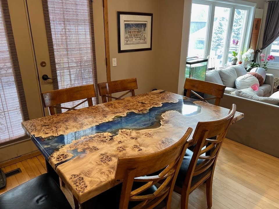 Spectacular maple burl blue ocean epoxy river dining table installed with wood chairs — Calgary home