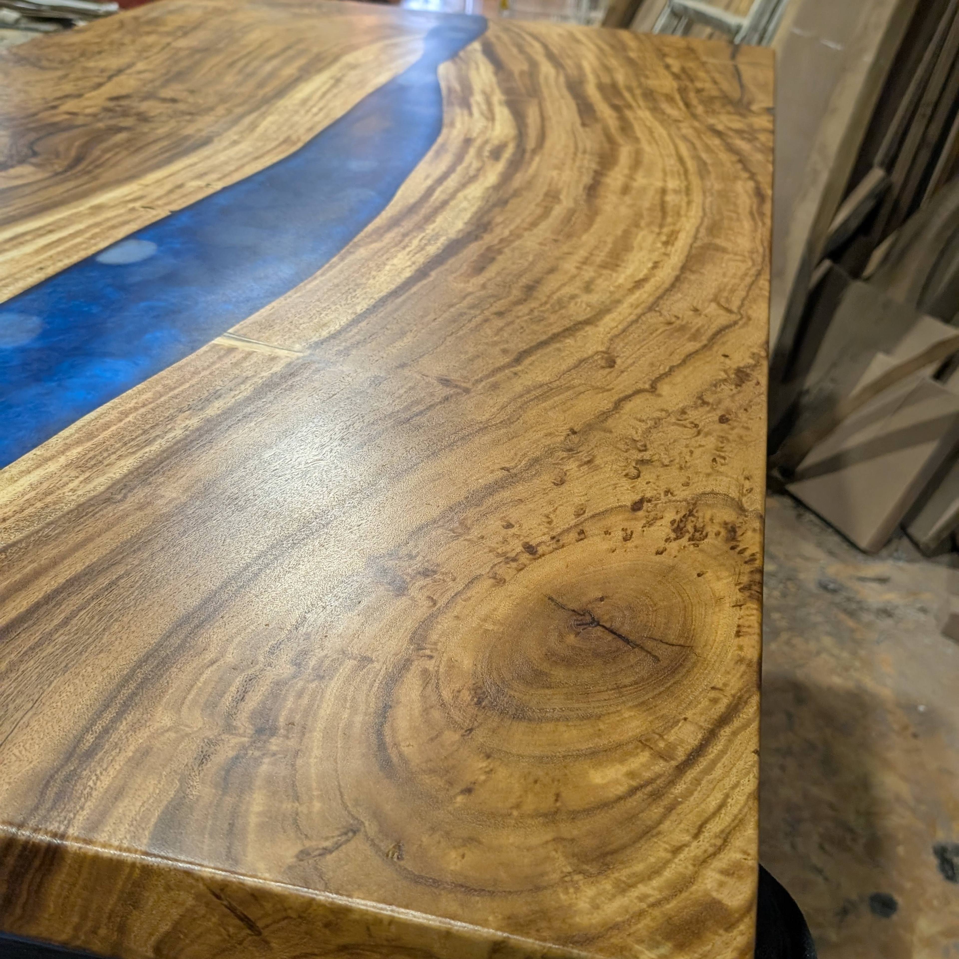 Live edge walnut blue epoxy river table — dramatic grain and burl closeup in Calgary Wood Works shop