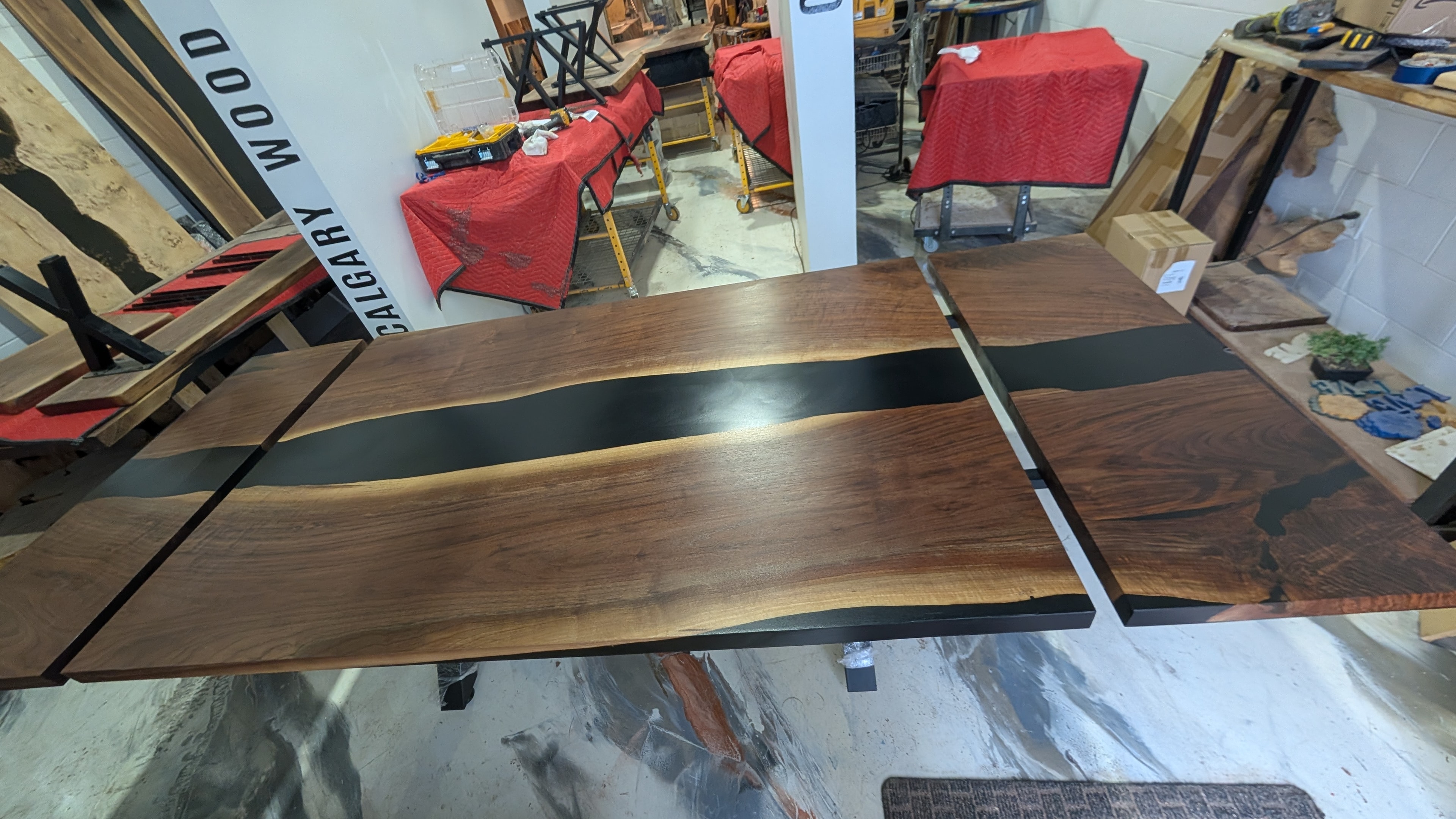 Custom expandable walnut black epoxy river dining table — overhead view fully extended in Calgary Wood Works shop