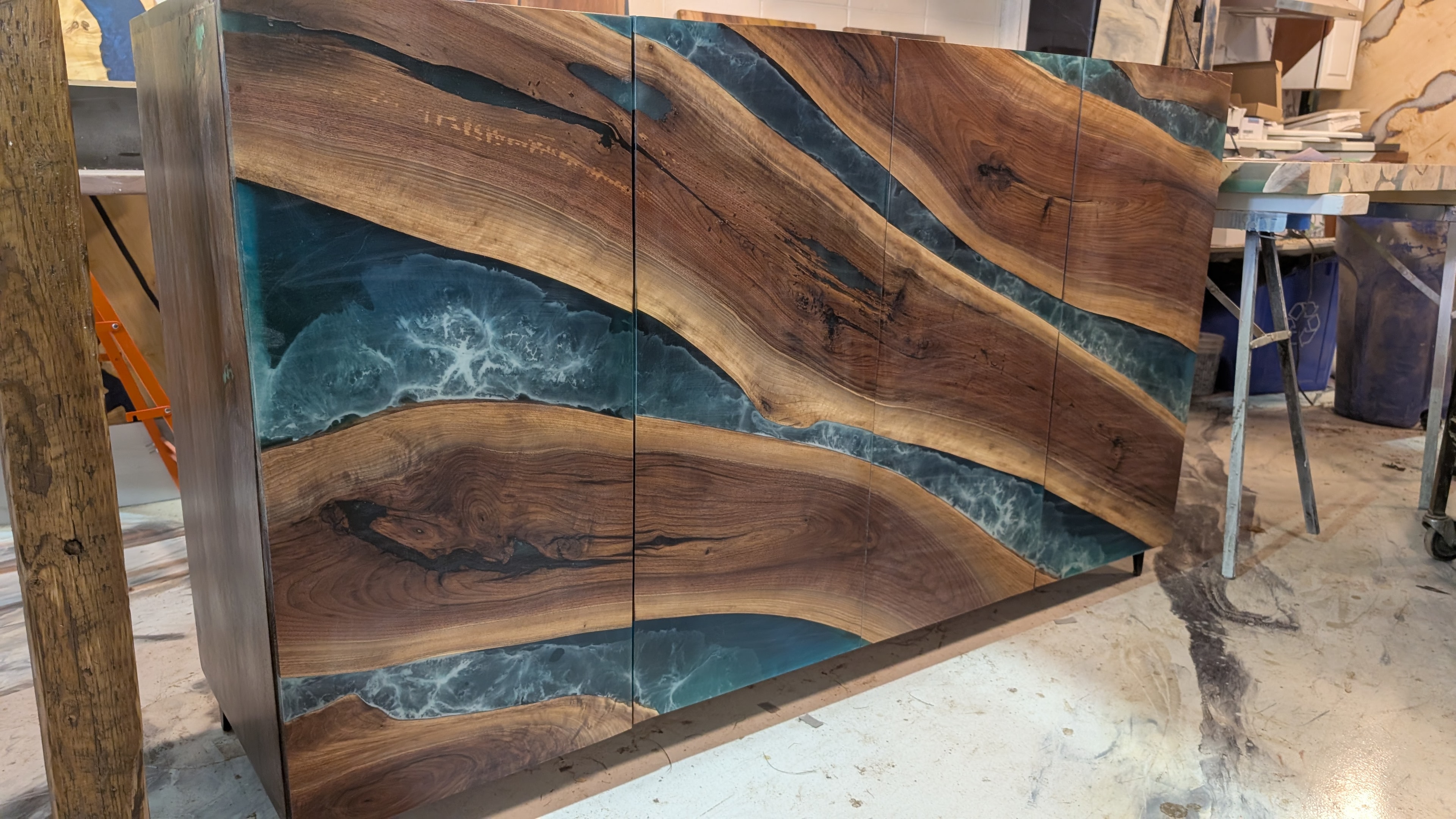 Custom walnut hutch with teal ocean epoxy river doors — angled closeup showing dramatic grain and epoxy detail