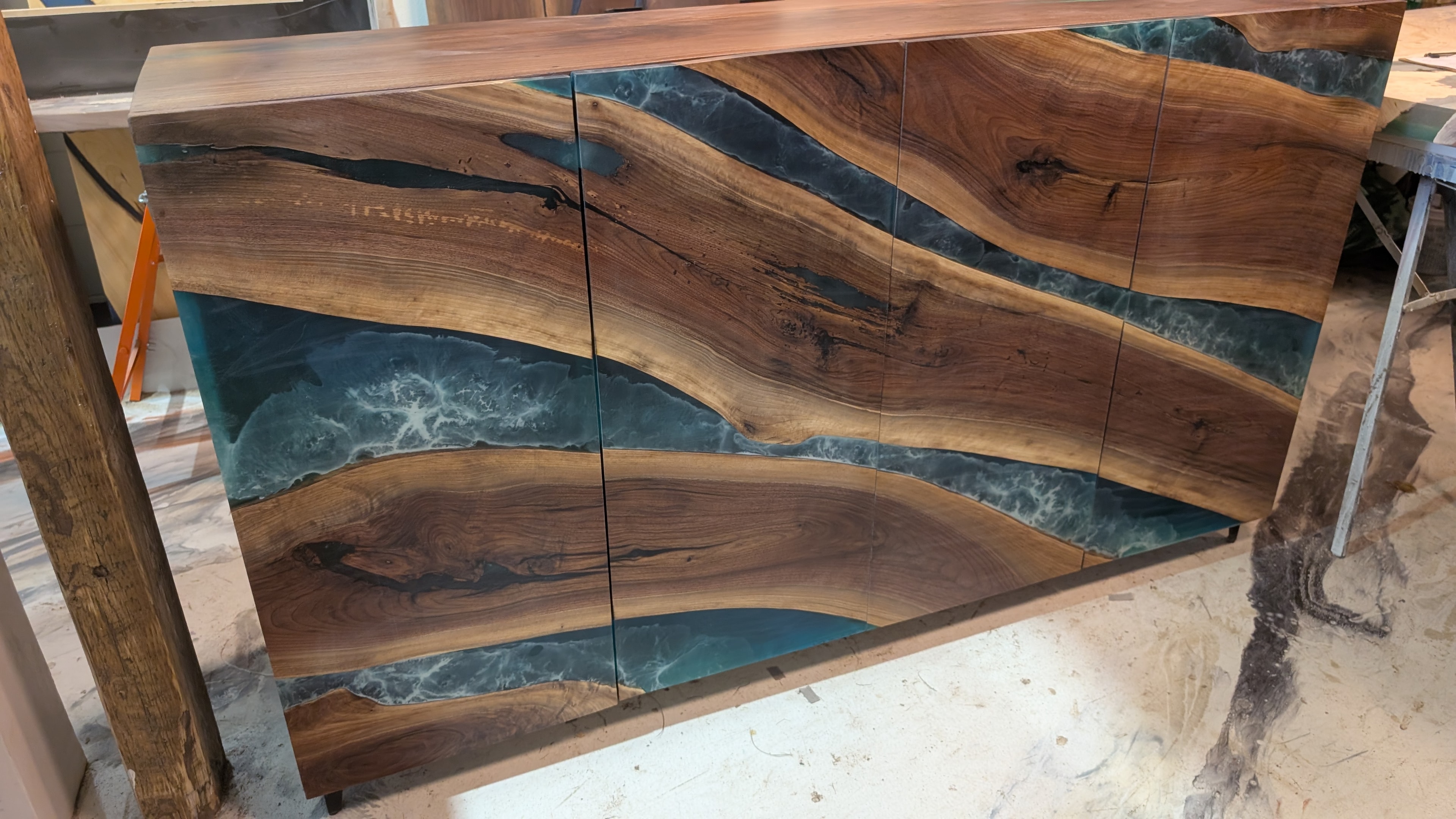 Custom walnut hutch with teal ocean epoxy river doors — straight-on front view, Calgary Wood Works shop