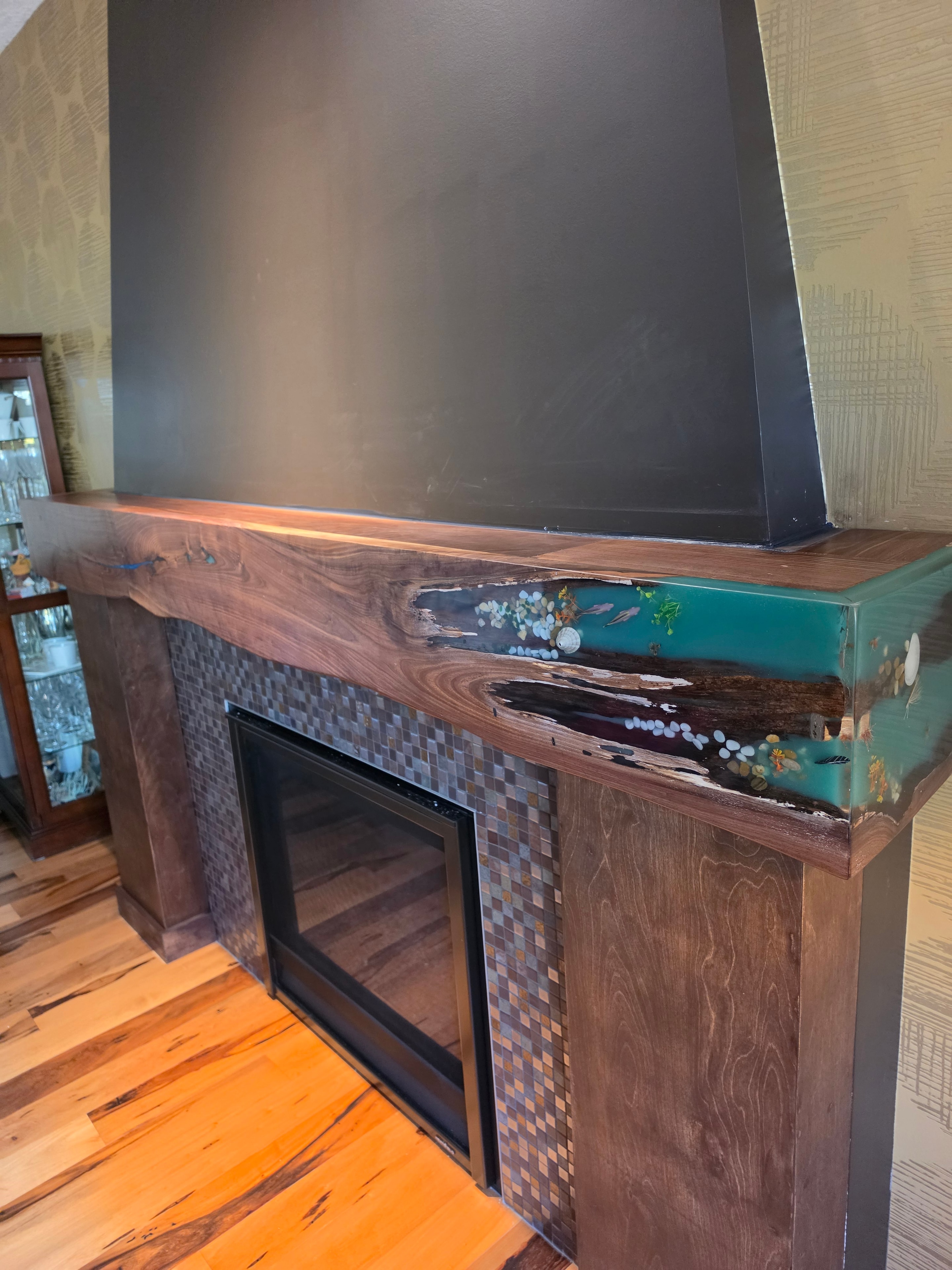 Close-up of teal ocean epoxy inlay on walnut fireplace mantel with mosaic tile surround — Calgary Wood Works