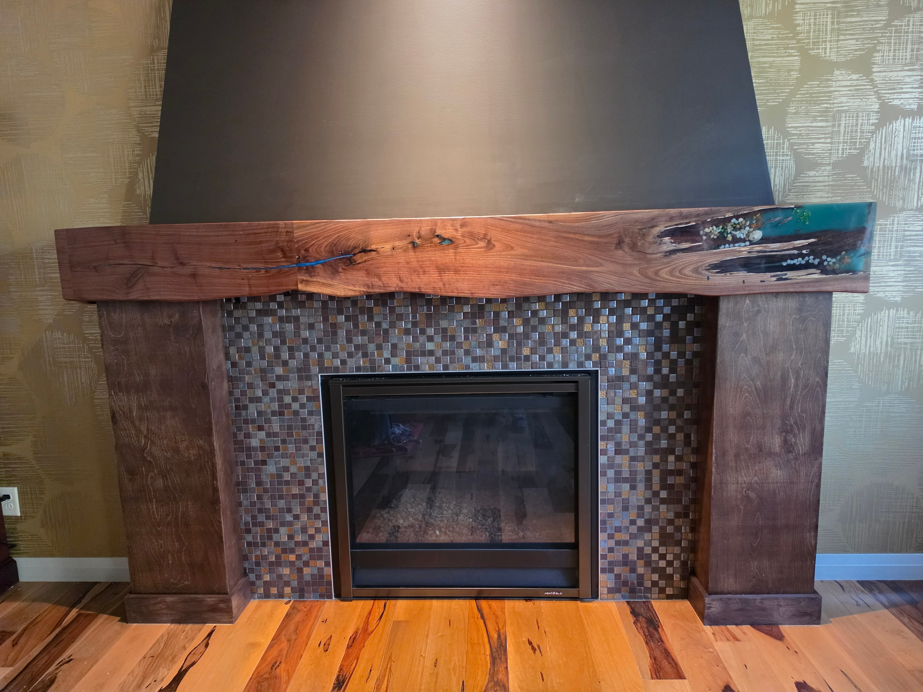 Custom walnut fireplace surround with teal ocean epoxy inlay and mosaic tile — Calgary Wood Works