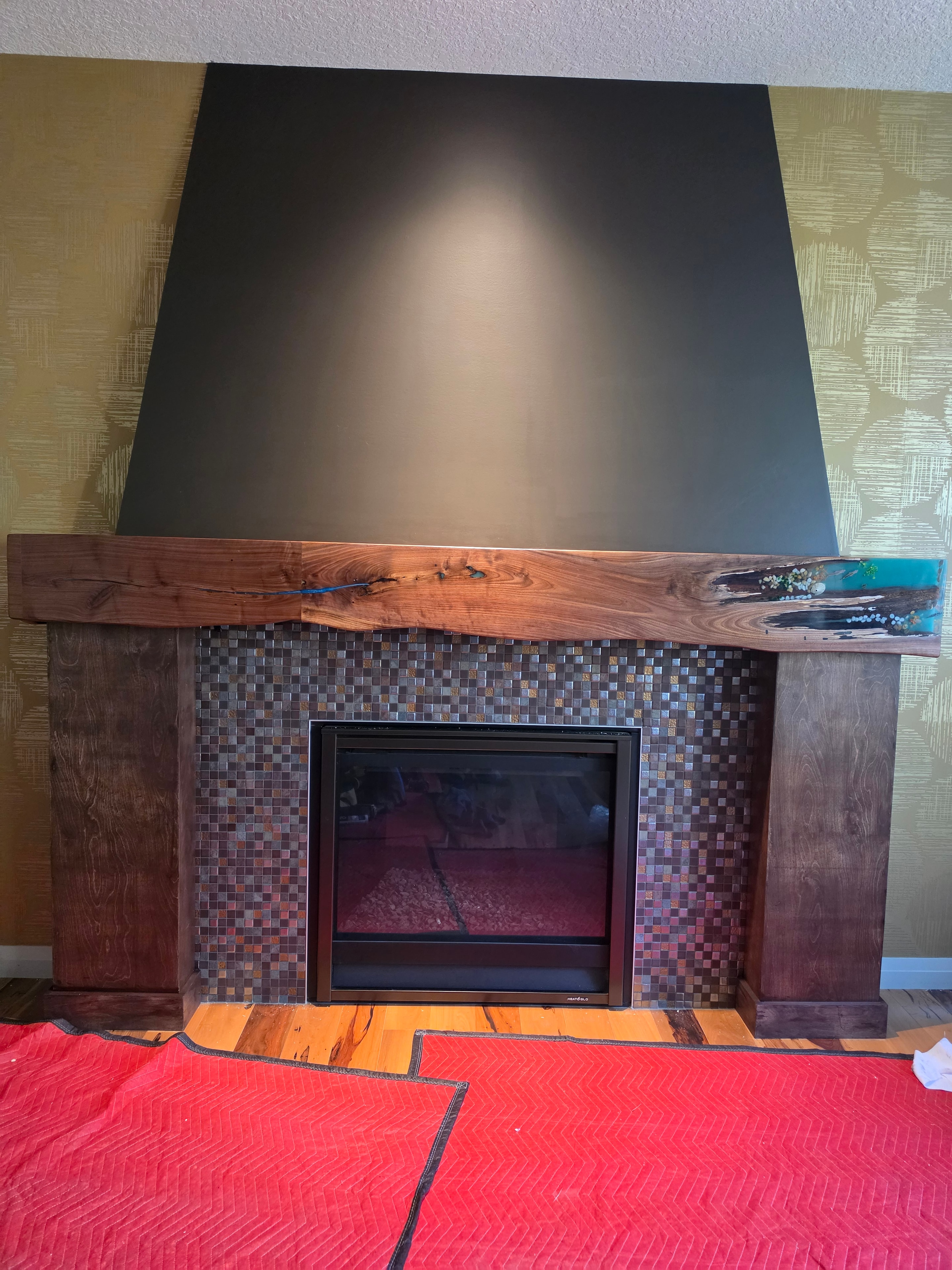 Walnut fireplace surround with teal epoxy inlay during installation — Calgary Wood Works