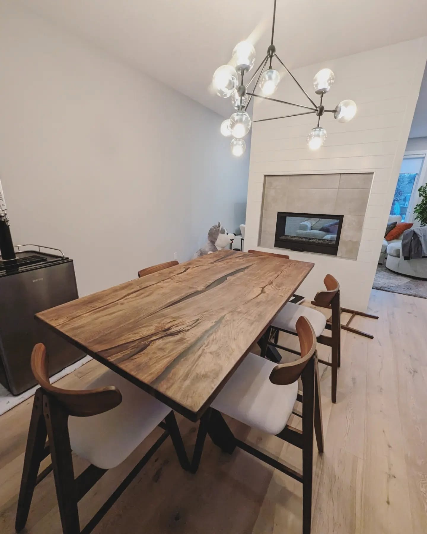 Solid spalted maple dining table with black epoxy void fills and X-base — modern dining room with sputnik chandelier
